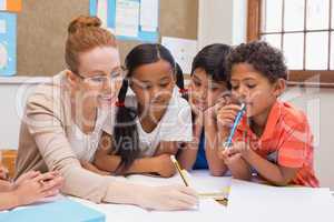 Teacher and pupils working at desk together