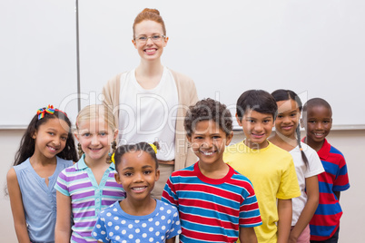 Teacher and pupils smiling at camera in classroom