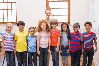 Teacher and pupils smiling at camera in classroom