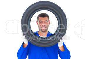 Happy mechanic looking through tire