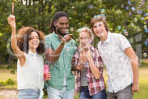 Happy friends in the park blowing bubbles