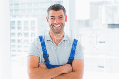 Portrait of smiling handyman standing arms crossed in office