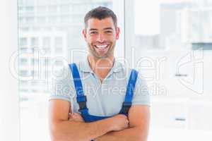 Portrait of smiling handyman standing arms crossed in office