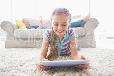 Happy girl using digital tablet on rug at home