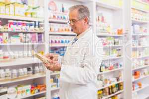 Smiling senior pharmacist reading prescription