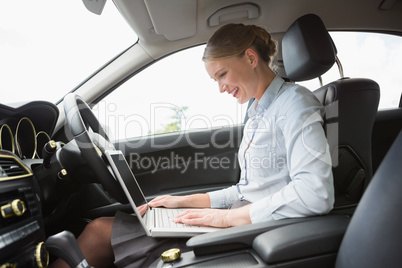 Businesswoman using laptop in the drivers seat