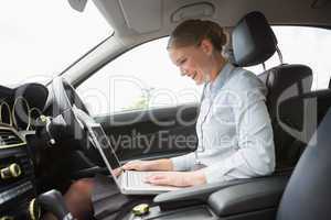 Businesswoman using laptop in the drivers seat