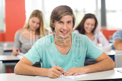 Male student writing notes in classroom