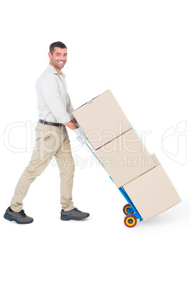 Happy delivery man pushing trolley of boxes