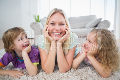 Children looking at mother lying on rug