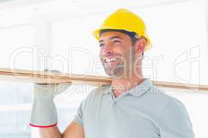 Smiling handyman carrying wood