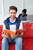 Smiling casual young man reading folder in office