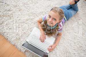 Cute girl using laptop while lying on rug