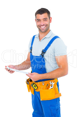 Happy carpenter in overalls holding clipboard