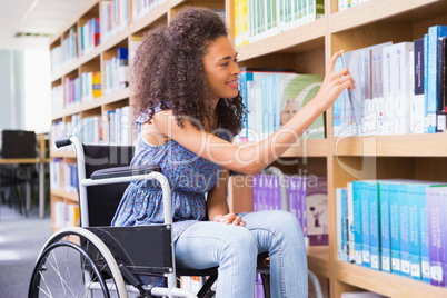 Smiling disabled student in library picking book