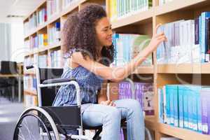 Smiling disabled student in library picking book