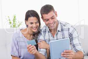 Couple shopping online on digital tablet using credit card