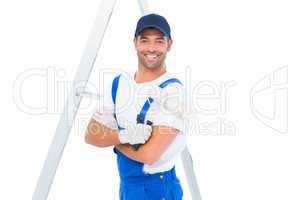 Smiling handyman with paint roller standing by ladder