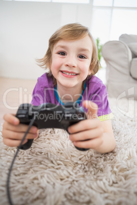 Happy boy playing video game while lying on rug