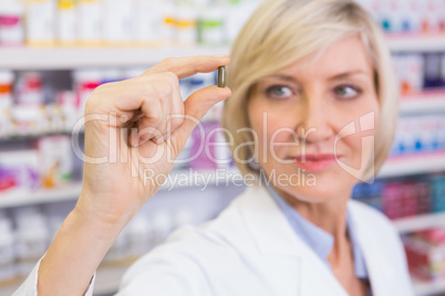 Blonde pharmacist in lab coats showing pill