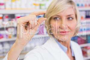 Blonde pharmacist in lab coats showing pill