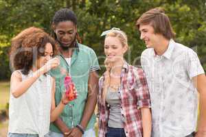 Happy friends in the park blowing bubbles