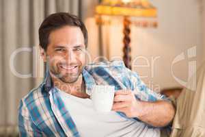 Handsome man relaxing on his bed with hot drink