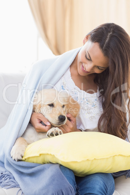 Woman playing with cute puppy on sofa