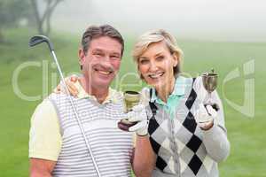 Happy golfing couple with trophy