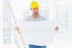 Male architect reading blueprint in office