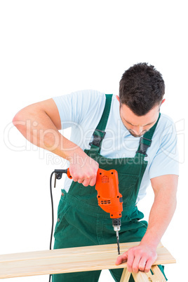 Carpenter drilling hole in plank