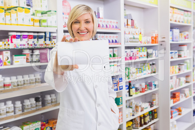 Smiling pharmacist showing paper at camera