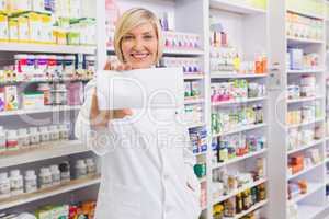 Smiling pharmacist showing paper at camera