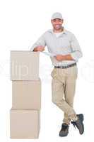 Delivery man with clipboard leaning on cardboard boxes