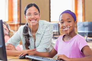 Cute pupil in computer class with teacher