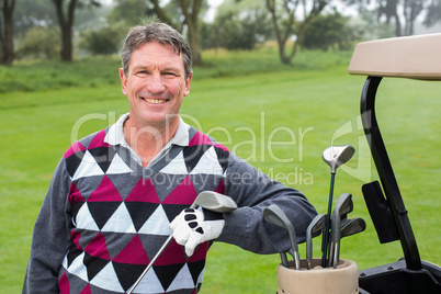 Happy golfer beside his golf buggy