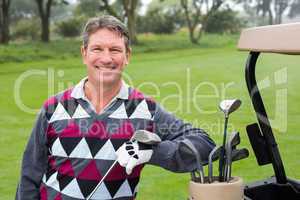 Happy golfer beside his golf buggy