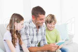 Man telling story to children while sitting on sofa