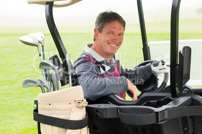 Happy golfer driving his golf buggy smiling at camera