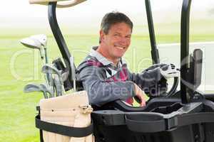 Happy golfer driving his golf buggy smiling at camera