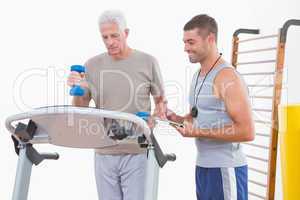 Senior man on treadmill with trainer