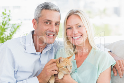 Portrait of happy couple playing with cat