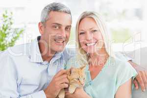 Portrait of happy couple playing with cat