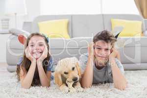 Happy siblings with puppy lying on rug