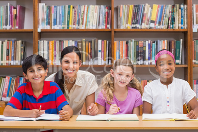 Pretty teacher helping pupils in library Pretty teacher helping pupils in library