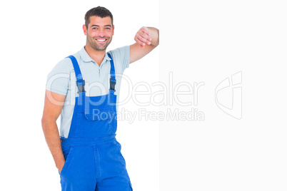 Happy repairman leaning on blank placard