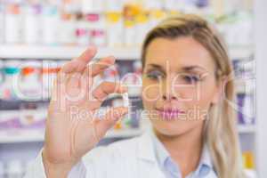 Smiling student in lab coat holding pill
