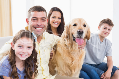 Smiling family sitting with Golden Retriever on sofa