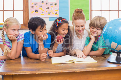 Cute pupils and teacher smiling at camera in classroom