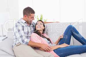 Couple looking at each other while relaxing on sofa